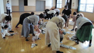 子供を掃除機に見たてて新聞紙を集める